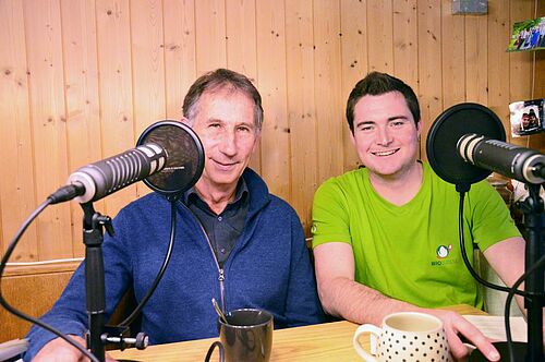 Zwei Männer vor dem Podcast-Mikrophon