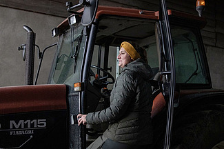 Frau steigt in einen Traktor.