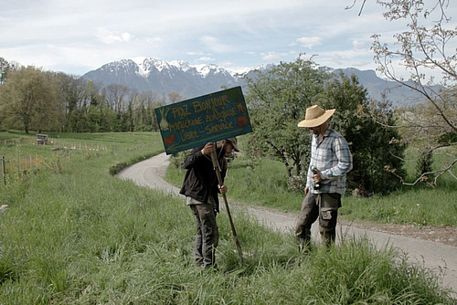 Zwei Menschen stellen ein Schild mit der Aufschrift "Praz Bonjour" in ein Feld.