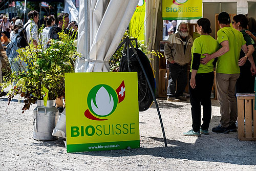 Die Knospe von Bio Suisse an einem Stand mit Menschen.