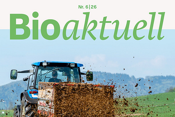 Titelseite Bioaktuell 6|26: Ein Traktor verteilt Mist auf Grünland.
