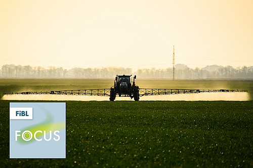 Ein Traktor mit einer Feldspritze auf einem Feld.