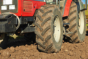 Eine Detailansicht der Reifen von einem roten Traktor auf einem Acker. 