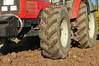 Eine Detailansicht der Reifen von einem roten Traktor auf einem Acker. 