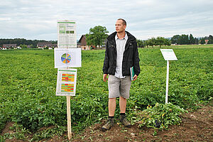Berater vor Kartoffelfeld zwischen zwei Stangen mit Postern