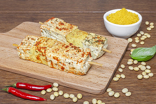 Zwei Spiesse mit Tofuwürfeln, Gewürz drauf und etwas Deko rundum.