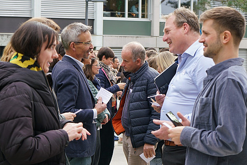 Zahlreiche Menschen stehen sich in zwei Reihen gegenüber und diskutieren.