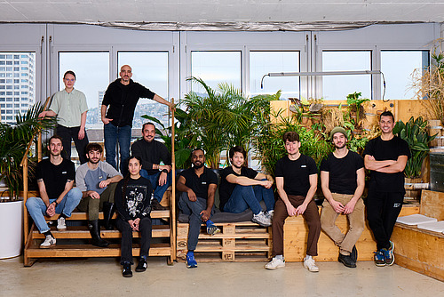 Eine Gruppe von Menschen unterschiedlichen Alters auf einer Treppenkonstruktion in einem Bürogebäude.