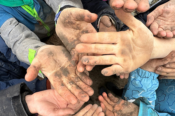 Verschieden grosse Hände mit Arbeitsdreck werden in die Kamera gestreckt.