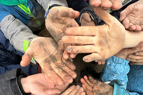 Verschieden grosse Hände mit Arbeitsdreck werden in die Kamera gestreckt.