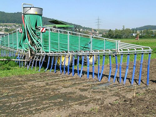 Schleppschlauchgerät an Traktor im Einsatz auf flachem Feld