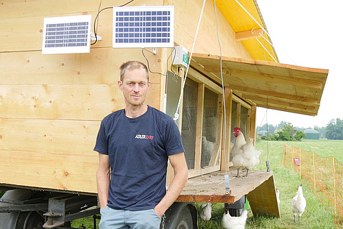 Ein Mann vor einem mobilen Hühnerstall.