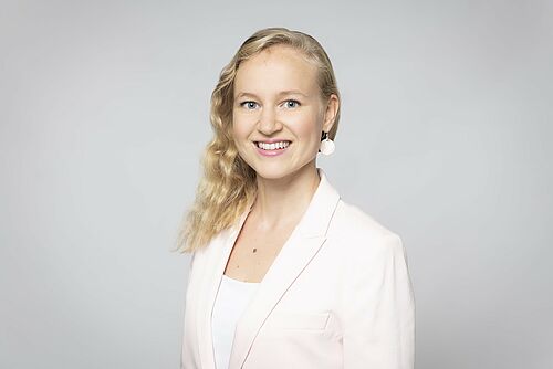 Eine blonde Frau vor einem grauen Hintergrund.