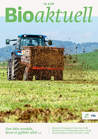 Titelseite Bioaktuell 6|26: Ein Traktor verteilt Mist auf Grünland.
