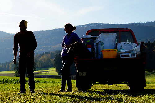 Bauer und Bäuerin neben Auto mit offener Ladefläche