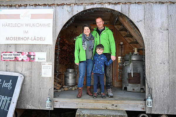 Eltern stehen mit ihrem Kind in der Tür des Hofladens.