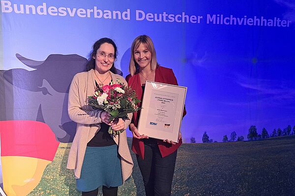 Zwei Frauen vor einem Plakat mit Kuh.