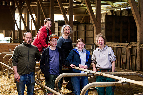 Ein Gruppenbild mit Menschen verschiedenen Alters in einem Stall. 