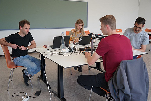 Menschen sitzen mit Laptops an einem Tisch und testen eine Applikation.