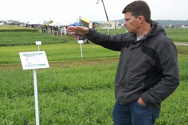 Mann referiert vor Grasversuchsflächen
