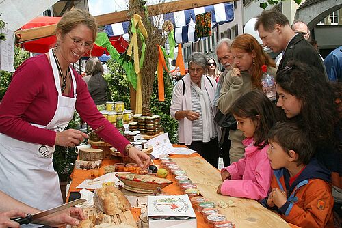 Bäuerin am Verkaufsstand mit vielen Besuchern