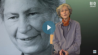 Autorin Diana Bach vor dem schwarz-weiss Porträt von Maria Müller, in der Mitte ein Play-Button