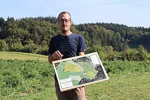 Ein Mann auf dem Feld mit einem Plan in der Hand.