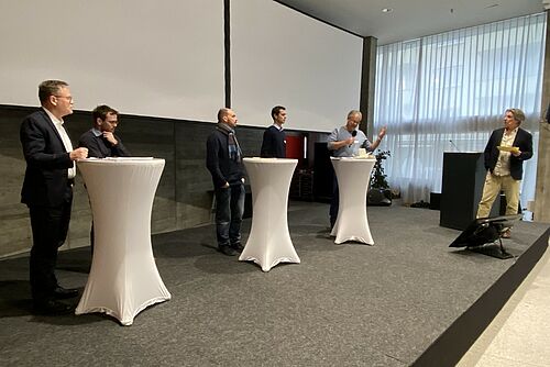 Sechs Männer auf einem Podium.