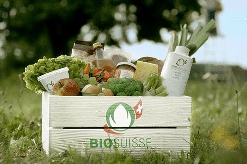 Mit Nahrungsmitteiln gefüllte Kiste mit Bio Suisse Logo  auf einer Wiese