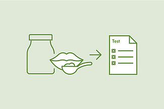 Eine Flasche und ein Mund mit einem Testlöffel zeigen auf einen Papierbogen mit der Aufschrift "Test". 