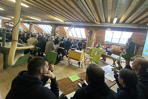 Eine Vereinsversammlung in einer Holzwerkstatt.