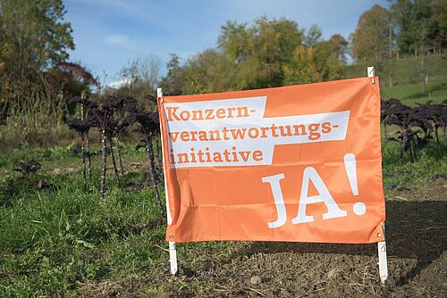 Flagge zur Konzernverantwortungsinitiative auf einem Feld