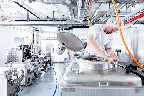 Ein Mitarbeiter macht sich in einem Milchverarbeitungsbetrieb an einem Tank zu schaffen. 