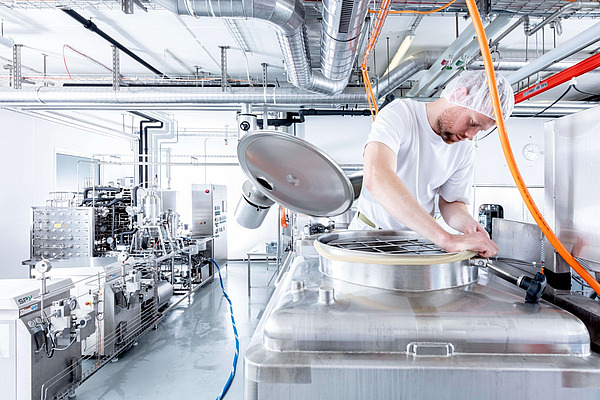 Ein Mitarbeiter macht sich in einem Milchverarbeitungsbetrieb an einem Tank zu schaffen. 