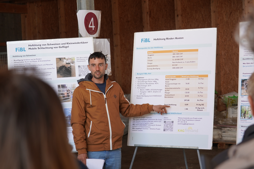 Ein Mann referiert in einem Stall vor zwei Flipcharts.