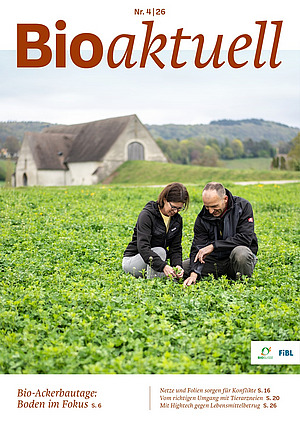 Titelseite Bioaktuell 4|26: Ein Mann und eine Frau kauern in einem Feld.