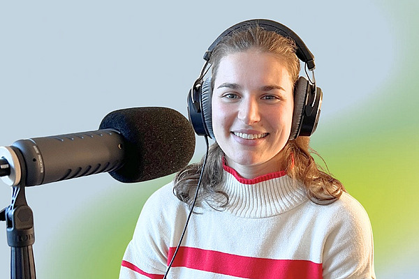 Eine Frau mit Kopfhörern an einem Podcast-Mikrofon.