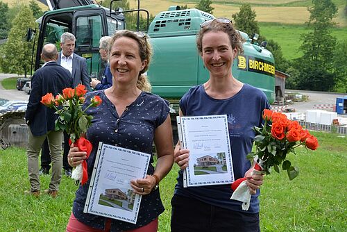 Zwei Frauen mit orangen Rosen und je einer Preisurkunde