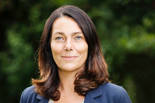 Franziska Herren blickt in die Kamera vor einem grünen Hintergrund. 