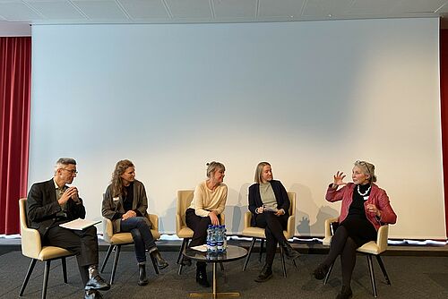 Eine Podiumsrunde debattiert auf einer Bühne. 