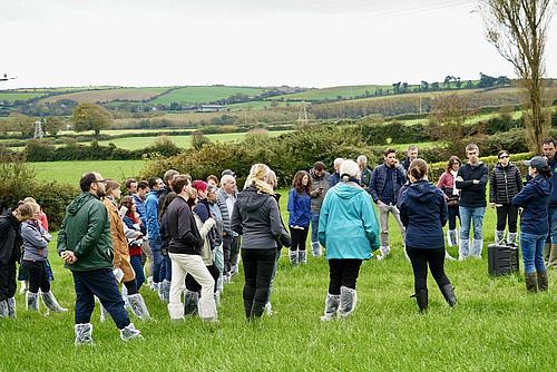 Menschen stehen auf einem Feld im Rahmen einer Betriebsbesichtigung.