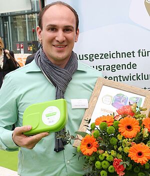 Mann mit grüner Box und Blumenstrauss