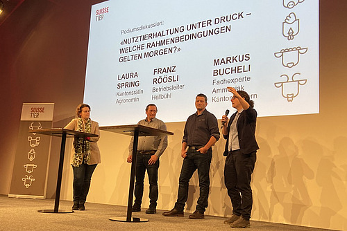 Zwei Frauen und zwei Männer diskutieren auf einer Bühne an Stehtischchen. 