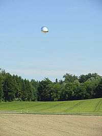 Folienballon hoch über einem Maisfeld schwebend