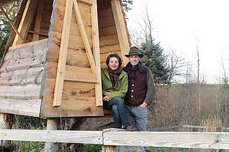 Mann und Frau vor einem Holzhäuschen