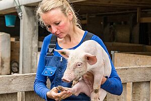 Nele Quander hält ein Ferkel unter dem Linken Arm.