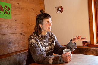 Julia Meier Maggini im Gespräch mit Teetasse in der Hand am Tisch.