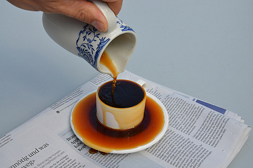 Kaffee läuft über eine Tassetasse hinaus. 