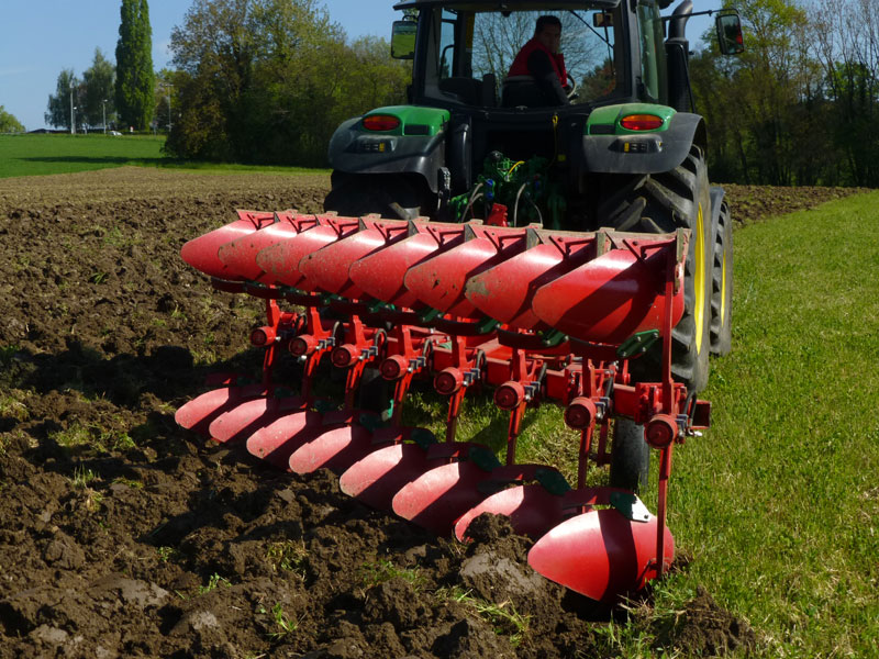 Roter Pflug im Einsatz in einer Wiese.